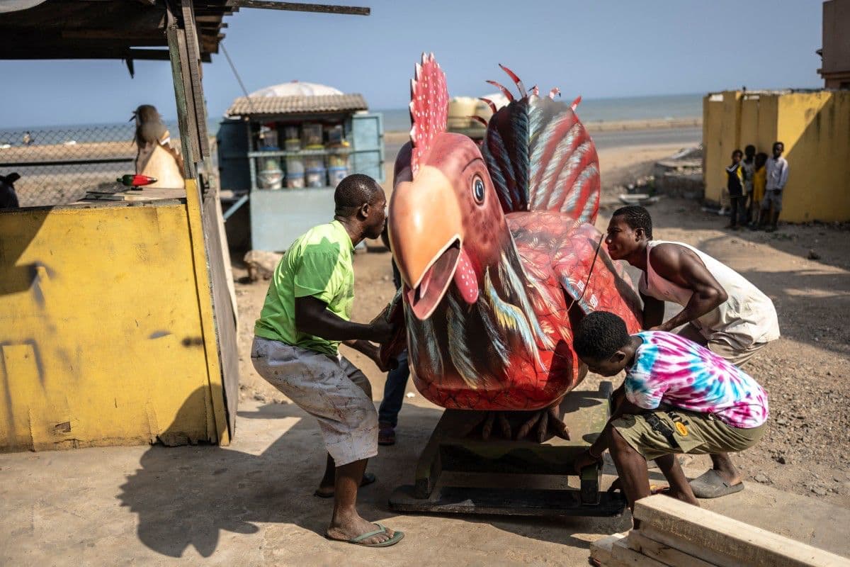 <b>Un pollo de madera para despedir a un agricultor:</b> Eric Adotey Kpakpo, conocido como Erico, y varios trabajadores de su taller trasladan un enorme ataúd con forma de pollo. La pieza fue creada para un agricultor y muestra la imaginación con la que estos artesanos convierten los oficios cotidianos en esculturas funerarias.