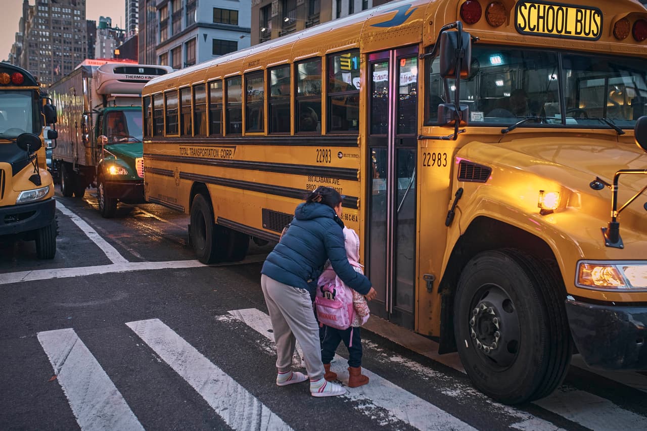 Migrantes toman el autobús escolar frente a Row Hotel, uno de los albergues que ha habilitado la ciudad