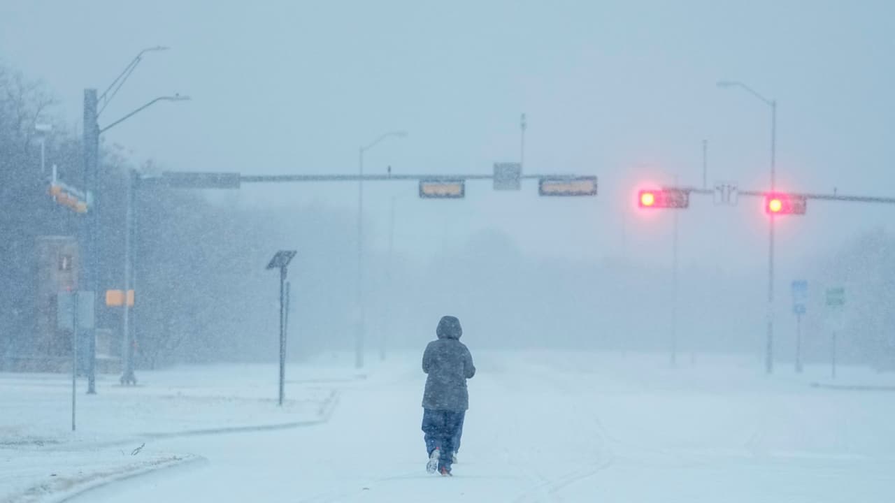 Una persona trota en una carretera cubierta de nieve, el lunes 15 de enero de 2024, en Grand Prairie, Texas.