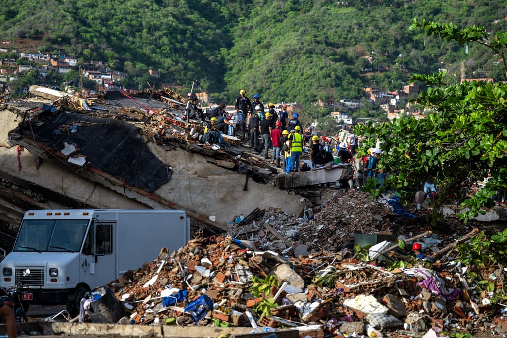 Equipos de rescate y voluntarios ayudan a buscar supervivientes entre los escombros de un edificio derrumbado en Caraballeda, estado de La Guaira, Venezuela, el 30 de junio de 2026, tras los terremotos gemelos del 24 de junio. (Miguel Medina/Pool Photo vía AP)