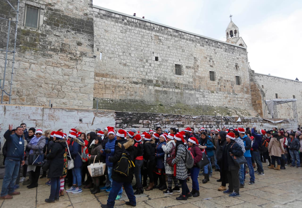 Los peregrinos cristianos llevan sombreros rojos de Santa Claus mientras esperan para entrar en la Iglesia de la Natividad.