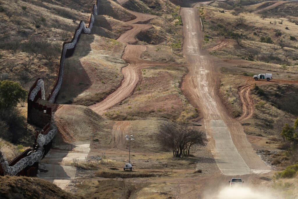 Un agente de Aduanas y Protección Fronteriza vigila desde el lado estadounidense un muro fronterizo.
