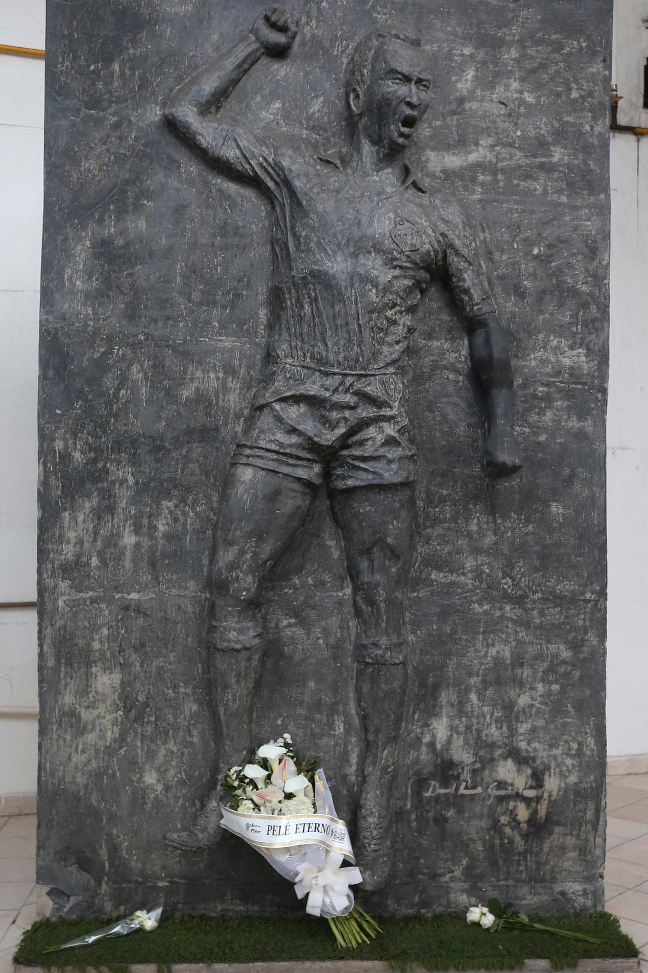 Fotografía de una escultura con la imagen de Pelé en la entrada principal del estadio del Santos. El legendario jugador será velado en público del lunes al martes en el estadio Vila Belmiro de Santos, ciudad a 80 km de Sao Paulo. El martes será llevado en un cortejo fúnebre que pasará por el lugar donde vive su madre, doña Celeste, de 100 años, hasta un mausoleo. Ahí su familia lo despedirá en privado, informó en una nota el Santos.