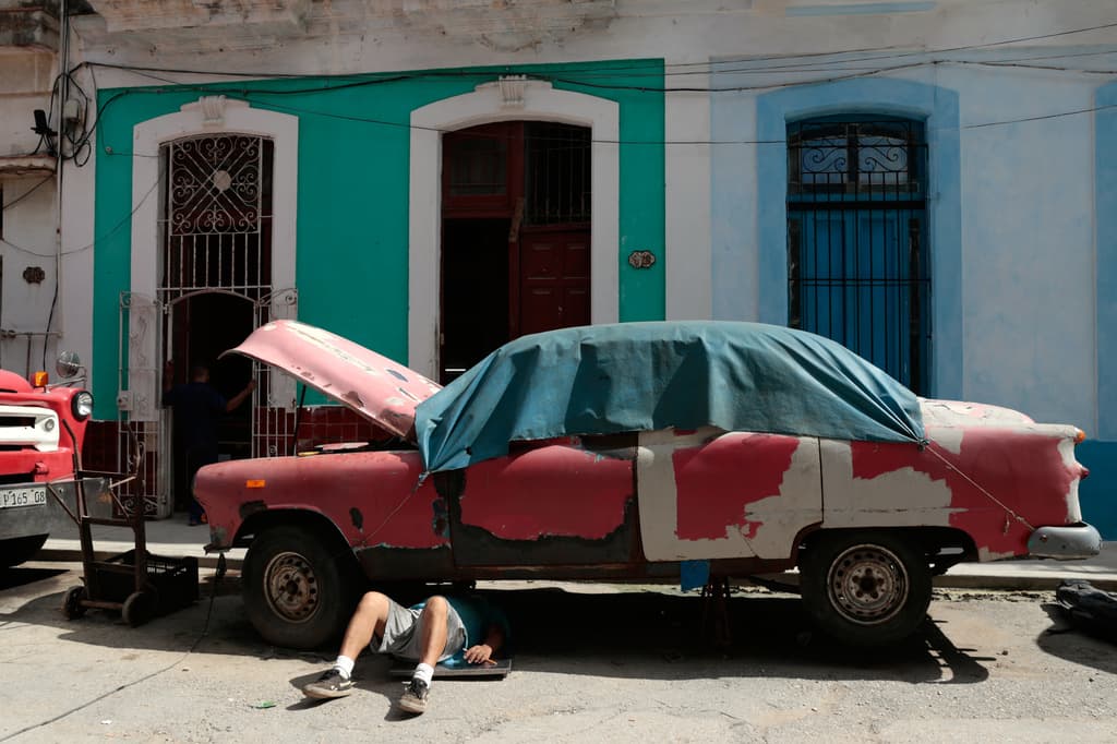 Un hombre trabaja en un automóvil clásico estadounidense en La Habana, Cuba, el miércoles 17 de junio de 2026. (Foto AP/Jorge Luis Banos)