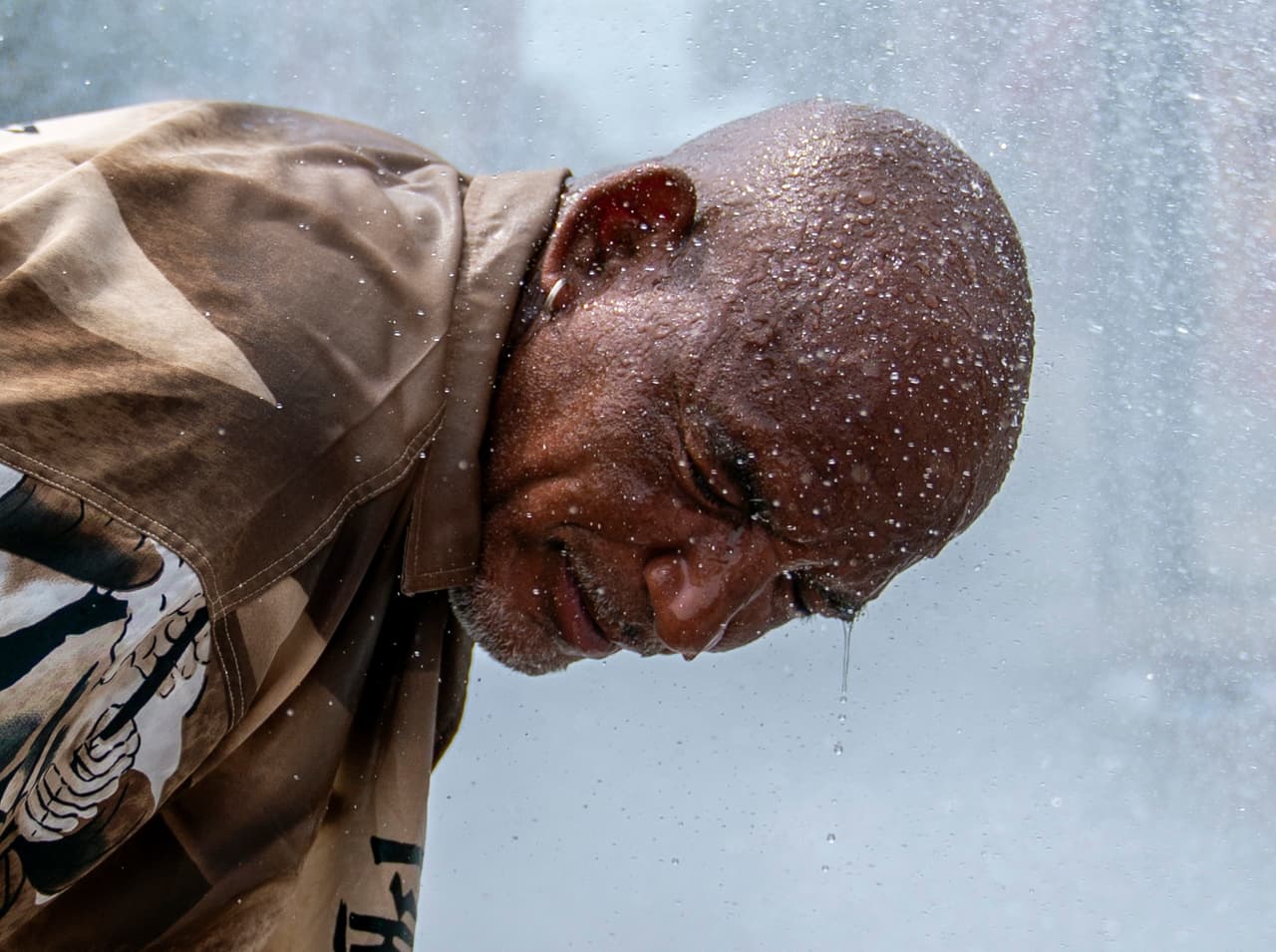 Un habitante se refresca en el chorro de agua producido por un hidrante de incendios.