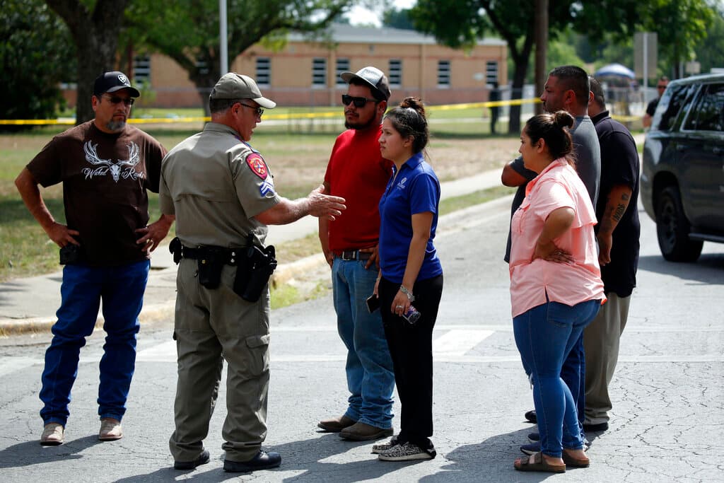 Un policía habla con personas que piden información fuera de la Escuela Primaria Robb en Uvalde, Texas, el martes 24 de mayo de 2022. Un hombre armado de 18 años abrió fuego en la escuela primaria de Texas y mató a varias personas. El gobernador Greg Abbott dice que el hombre armado ingresó a la escuela con una pistola y posiblemente un rifle. AP Photo/Darío López-Mills)