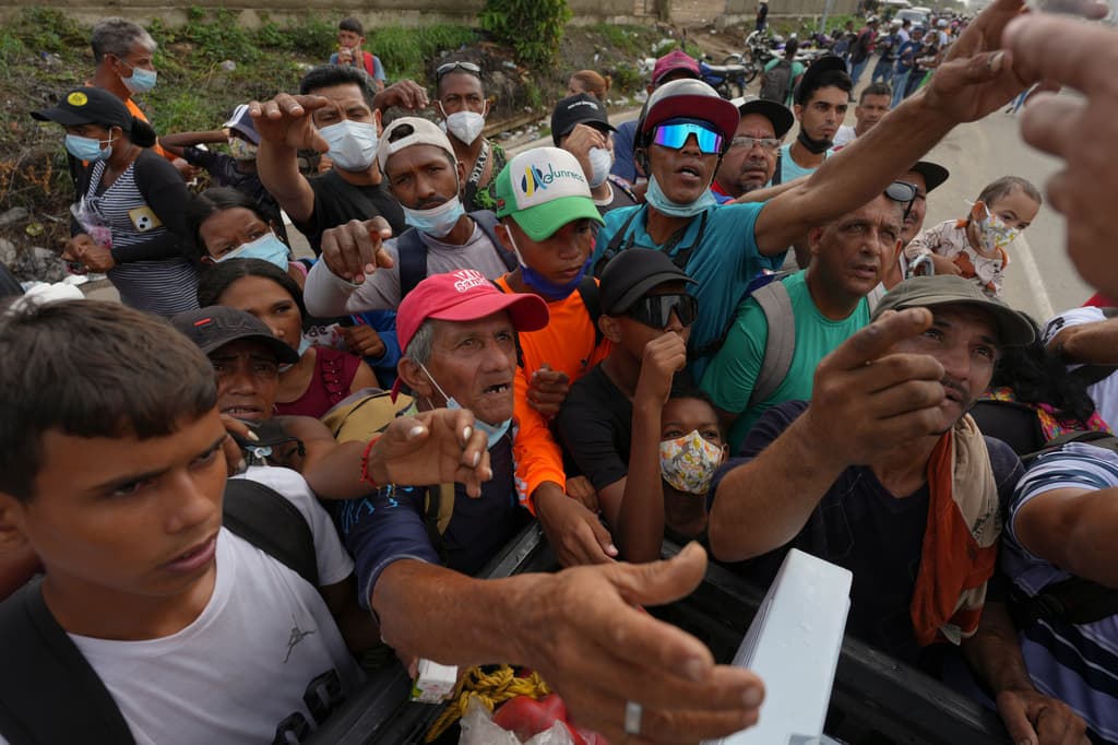 Personas extienden las manos para recibir suministros de voluntarios, días después de que un terremoto azotara La Guaira, Venezuela, el martes 30 de junio de 2026. (Foto AP/Matias Delacroix)