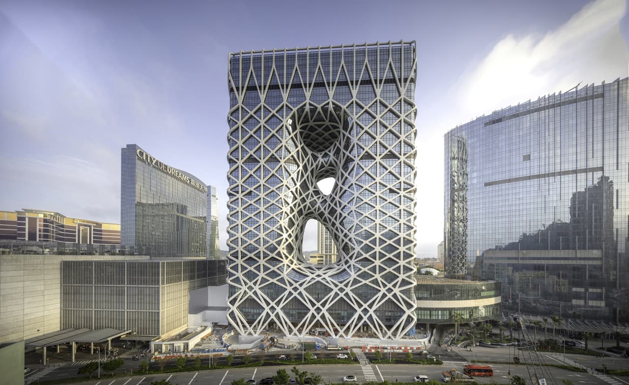 <b>Hotel Morfeo.</b> Está situado en el complejo turístico Ciudad de los Sueños de Cotai, Macao, China. El edificio presenta formas fluidas inspiradas en la tradicional talla del jade de ese país y lo atraviesan tres orificios asimétricos. Su exterior de cristal está recubierto por un esqueleto de acero en forma de red, lo que permite que su interior esté libre de columnas y muros de carga. Fue diseñado por
<a href="http://www.zaha-hadid.com" target="_blank">Zaha Hadid Architects. </a>