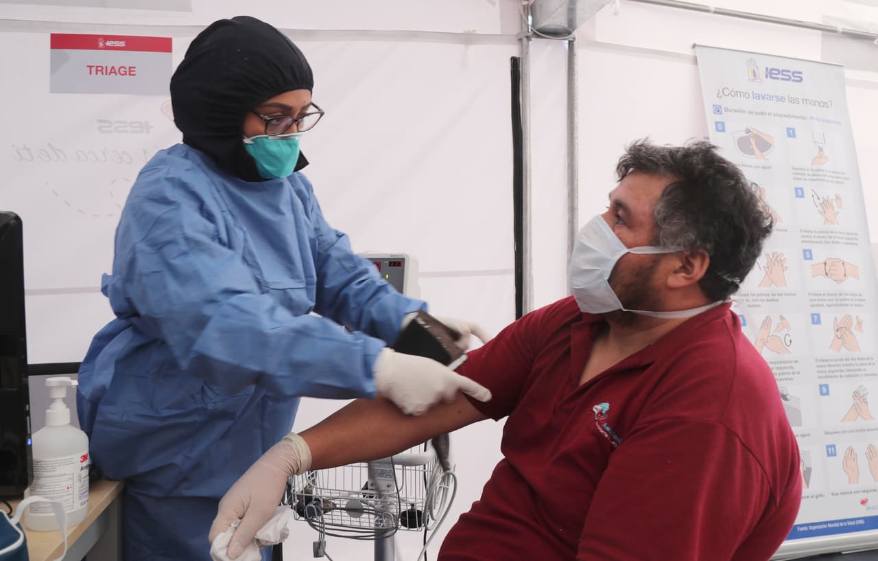 Un doctor examina a un hombre con síntomas relacionados al coronavirus en una carpa instalada a las afueras del Hospital del Seguro Social Quito Sur.