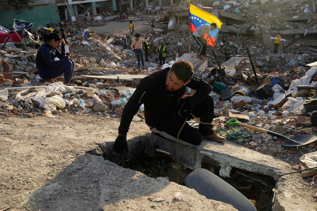 Jefferson Cova busca a sus hijos en un hueco que cavó junto a otros familiares entre los escombros de un edificio derrumbado por terremotos en La Guaira, Venezuela, el domingo 12 de julio de 2026. (Foto AP/Ariana Cubillos)