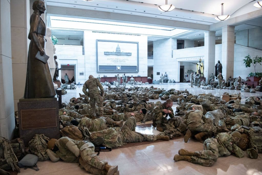 Efectivos de la Guardia Nacional reposan en el piso dentro del Capitolio el 13 de enero del 2021.