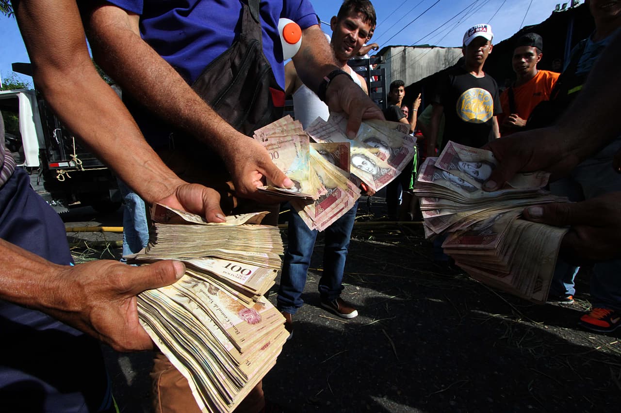 Un grupo de manifestantes muestra los billetes inservibles de 100 bolívares que no pudieron canjear en los bancos, mientras cierran una carretera en la ciudad de San Cristóbal, capital del estado de Táchira, fronterizo con Colombia.