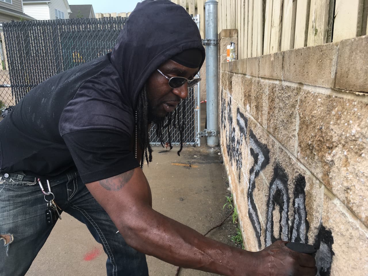 Tyree Colion pinta la consigna "No Shoot Zone" (Zona donde no se puede disparar) en el muro de una tienda en Baltimore