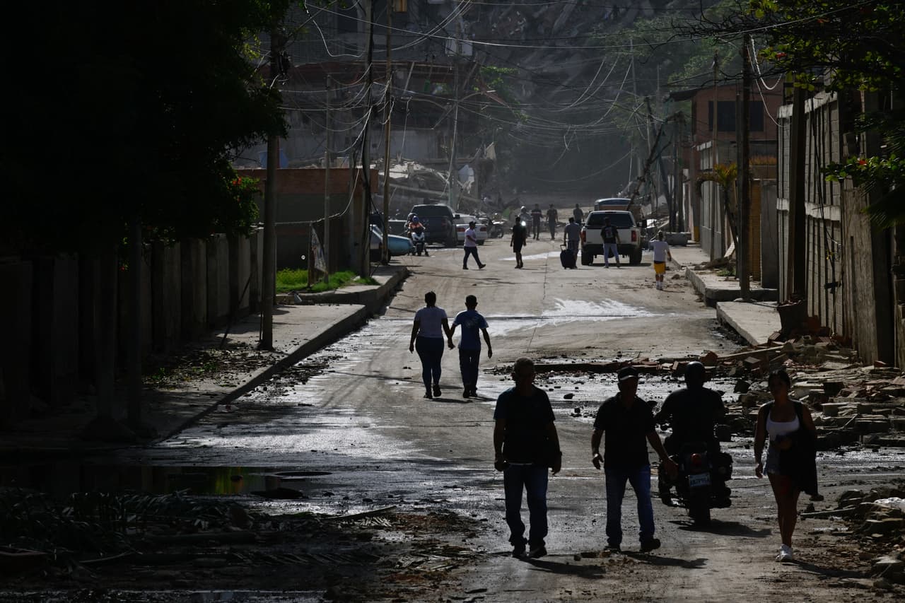 Personas caminan entre los escombros de edificios dañados tras los terremotos en La Guaira, Venezuela, el 25 de junio de 2026.