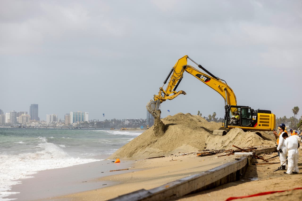 Trabajadores retiran arena mientras limpian los efectos de la tormenta tropical Rachel en la península de Alamitos, el domingo 11 de octubre de 2026, en Long Beach, California.