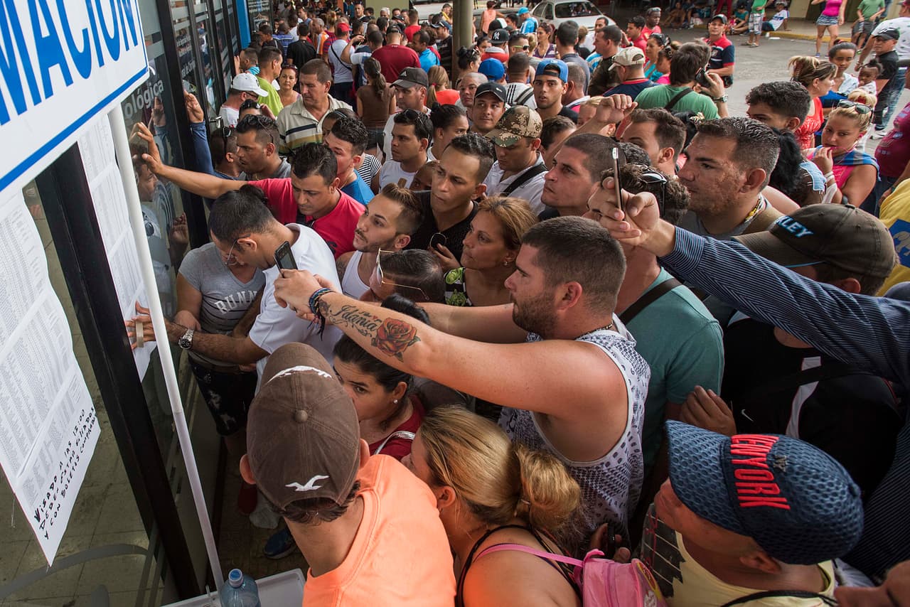 Después de meses de espera, hay impaciencia por retomar el viaje. Aquí, un grupo de cubanos revisa la lista con los nombres de los primeros que tomarán un avión para salir de Panamá.
