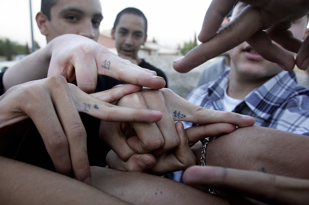 El Paso, UNITED STATES: 2/9 US-HISPANIC-GANGS In this photo released 19 April, 2006, members of the Pico Norte 19th Street gang pose flashing their hand signs and tattoos in El Paso, Texas. The gang, an offshoot of "Los Juaritos" gang from Ciudad Juarez, Mexico, has become the most notorious gang in the city with some 60 active members. The gang is known also for being a "clean gang" not involved in drug trafficking or part of older gangs that have become involved in large organize crime schemes. Some 650 known gang, the majority of hispanic-origin, operate in El Paso, according to the Onramp Youth Foundation, an organization that provides council to youths in trouble. Members say they joined the gang to gain respect among their peers and to protect themselves against other gangs, they consider the group a part of their family. AFP PHOTO/HECTOR MATA (Photo credit should read HECTOR MATA/AFP/Getty Images)