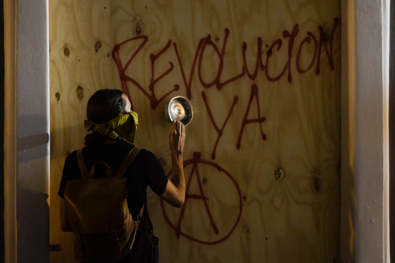Un manifestante le da a un panel de madera con una cacerola.
<br>