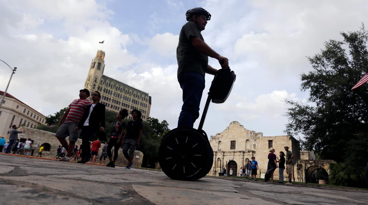 ARCHIVO - En esta foto de archivo del 8 de julio de 2015, un visitante pasa junto al Álamo en un Segway, en el centro de San Antonio. La antigua misión española del siglo XVIII está a punto de experimentar una de las transformaciones más significativas de su historia, ya que el estado planea comprar edificios comerciales cercanos e iniciar una revisión urbanística que podría generar cambios drásticos. (Foto AP/Eric Gay, Archivo)