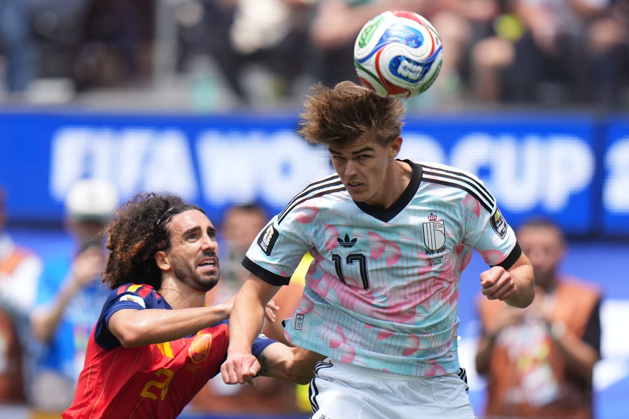 Charles De Ketelaere cabecea el balón mientras Marc Cucurella busca evitar una jugada peligrosa.