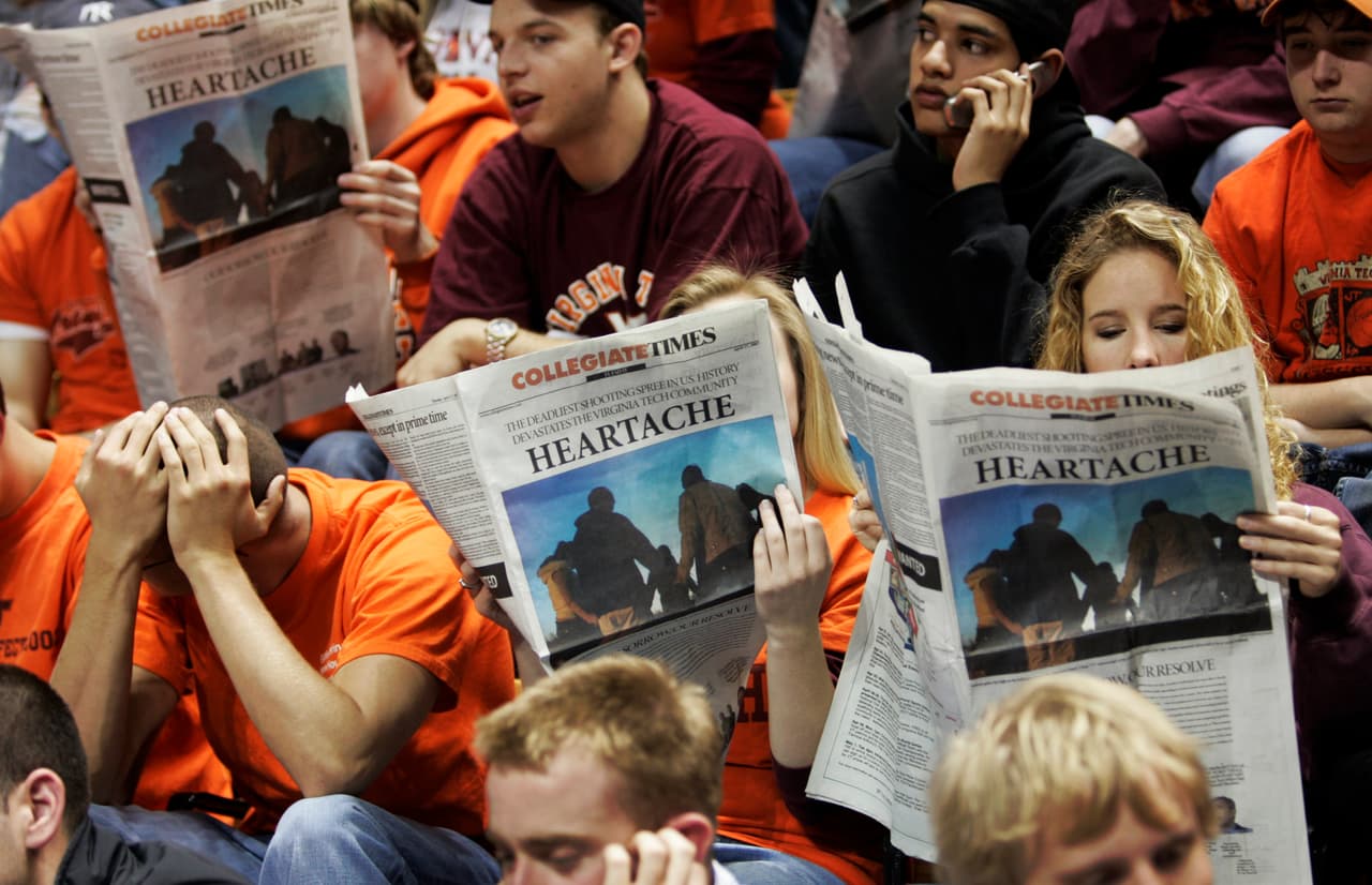 Estudiantes del Tecnológico de Virginia leen periódicos en los preliminares de una ceremonia para recordar a las víctimas en abril de 2017.