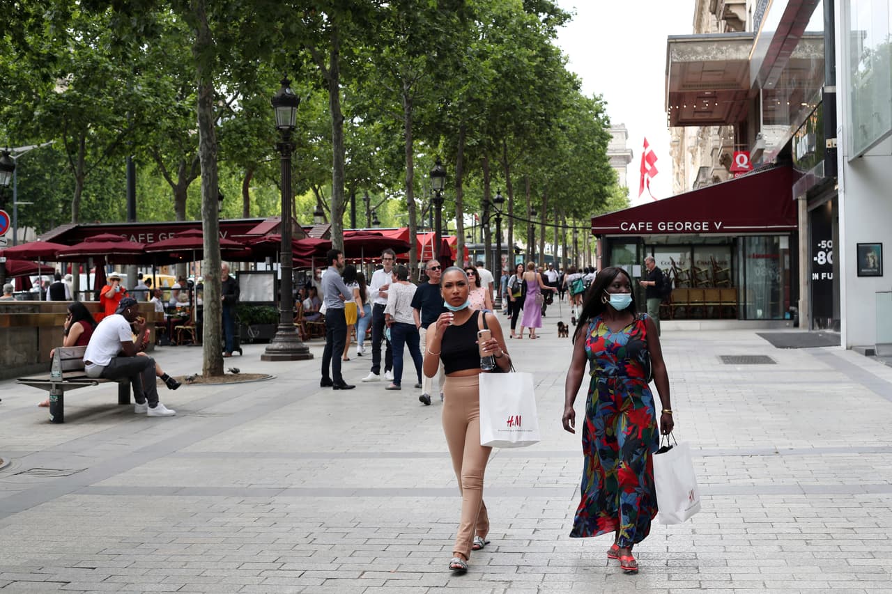 Personas con mascarillas caminan por la famosa avenida de los Campos Elíseos de París.