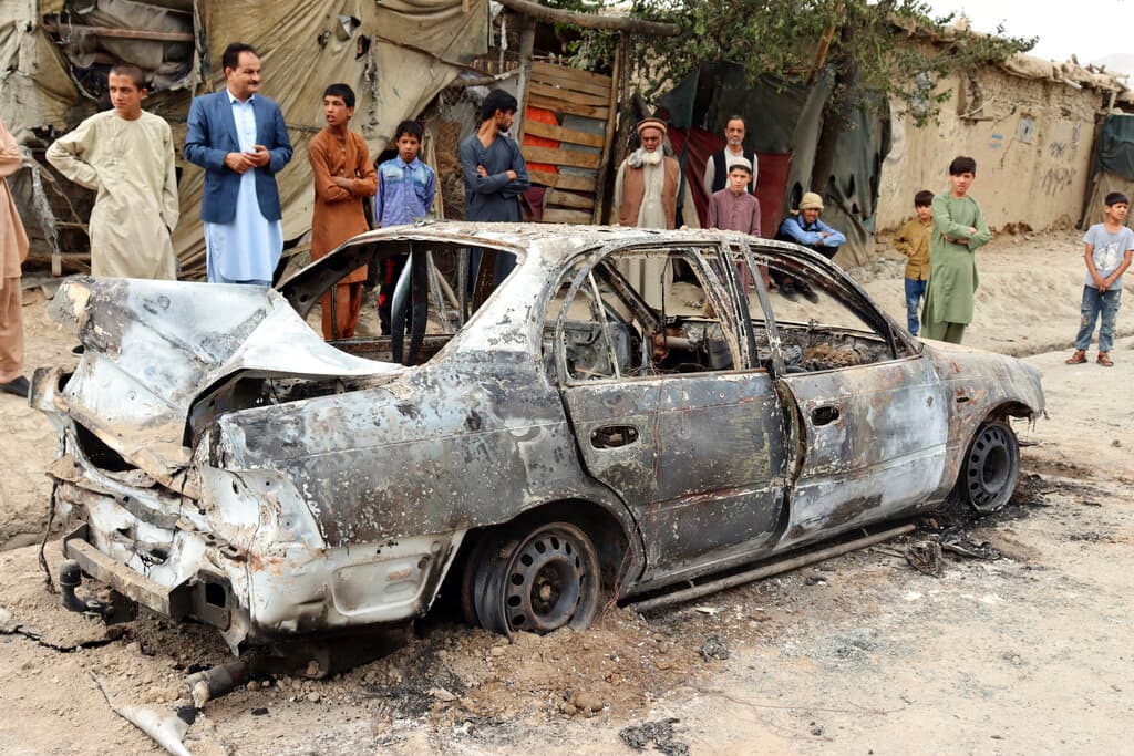 Vecinos de un barrio de Kabul miran un vehículo destruido que al parecer fue empleado para lanzar los proyectiles.