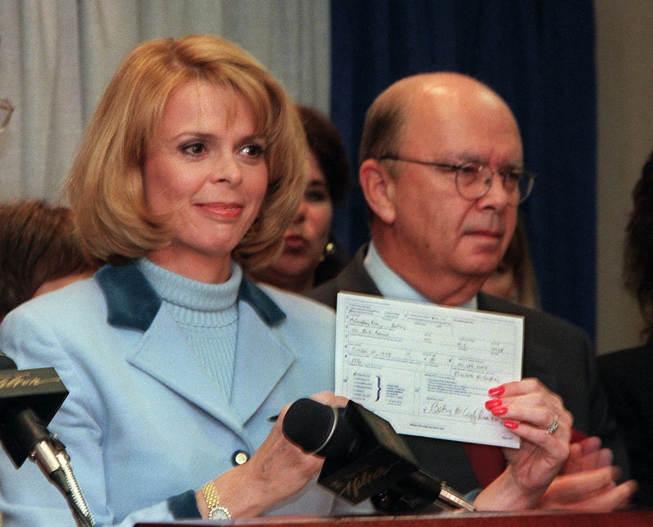 Wilbur Ross junto a su esposa Betsy McCaughey, vice gobernadora de Nueva York, cuando mostró la tarjeta de registro en el partido Demócrata. Había sido elegida por el partido Republicano pero por diferencias con el gobernador decidió cambiarse al partido Demócrata. Entonces Wilbur Ross estaba registrado como Demócrata sin embargo hizo donaciones a candidatos y organizaciones republicanas hasta que en 2016 se registró formalmente en ese partido.