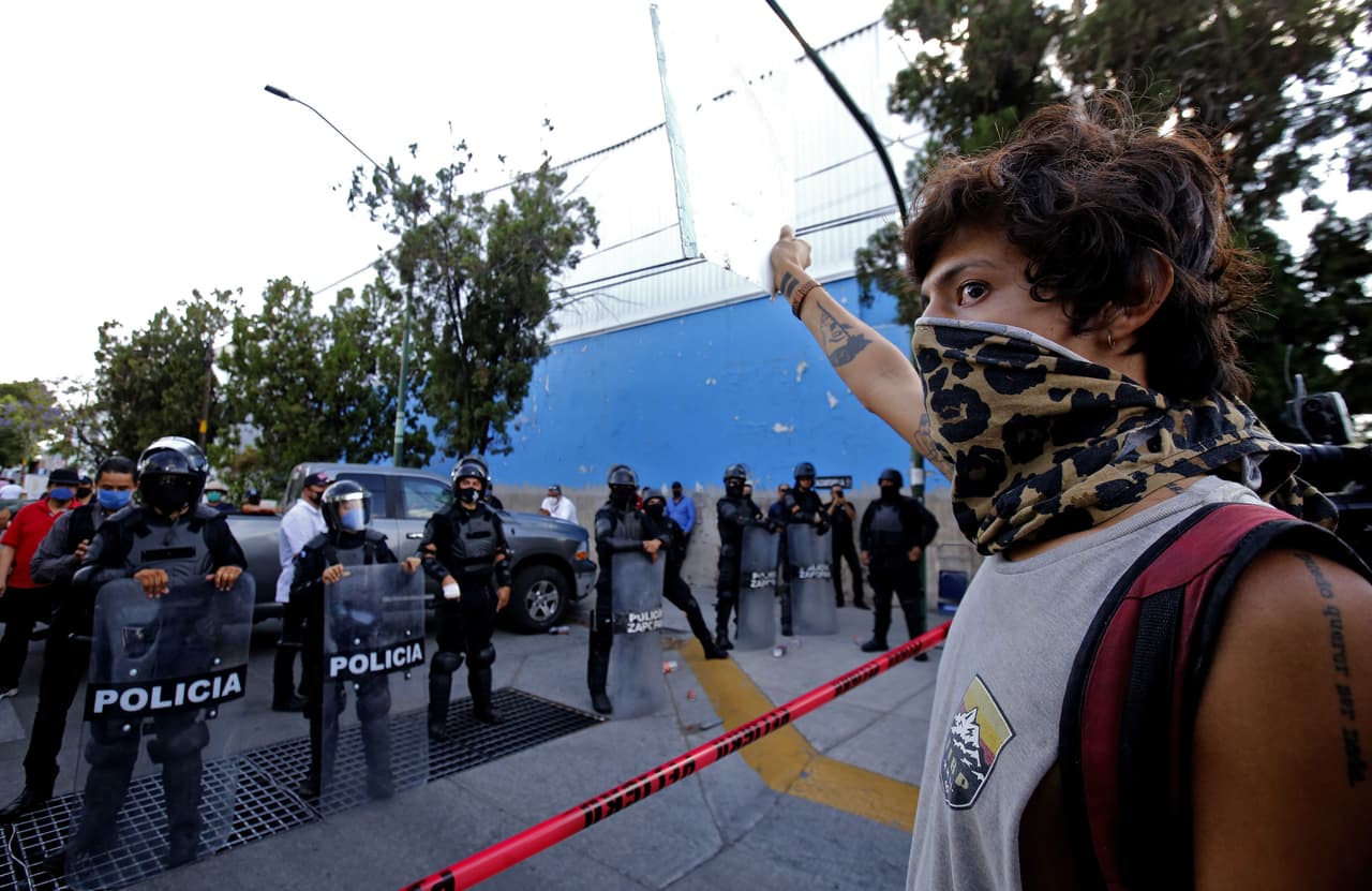 <h3 class="cms-H3-H3">7. Guadalajara, Jalisco </h3>
<br>
<b>(186 homicidios dolosos)</b>
<br>
<br>En imagen, un
<a href="https://www.univision.com/temas/manifestaciones">manifiestante</a> se para frente a una línea de policías antidisturbios tras la muerte de un joven mientras se encontraba bajo custodia policial, luego de haber sido arrestado presuntamente
<b> por no cumplir con las medidas para prevenir la propagación del coronavirus. </b>