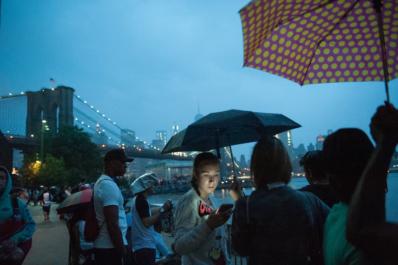 La gente de Nueva York espera los fuegos artificiales bajo la lluvia.