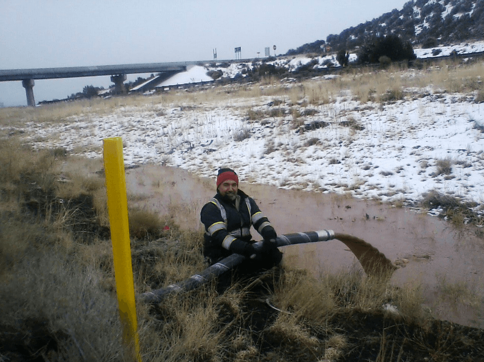 Obrero de Arizona removiendo el río de chocolate de una vía principal.
