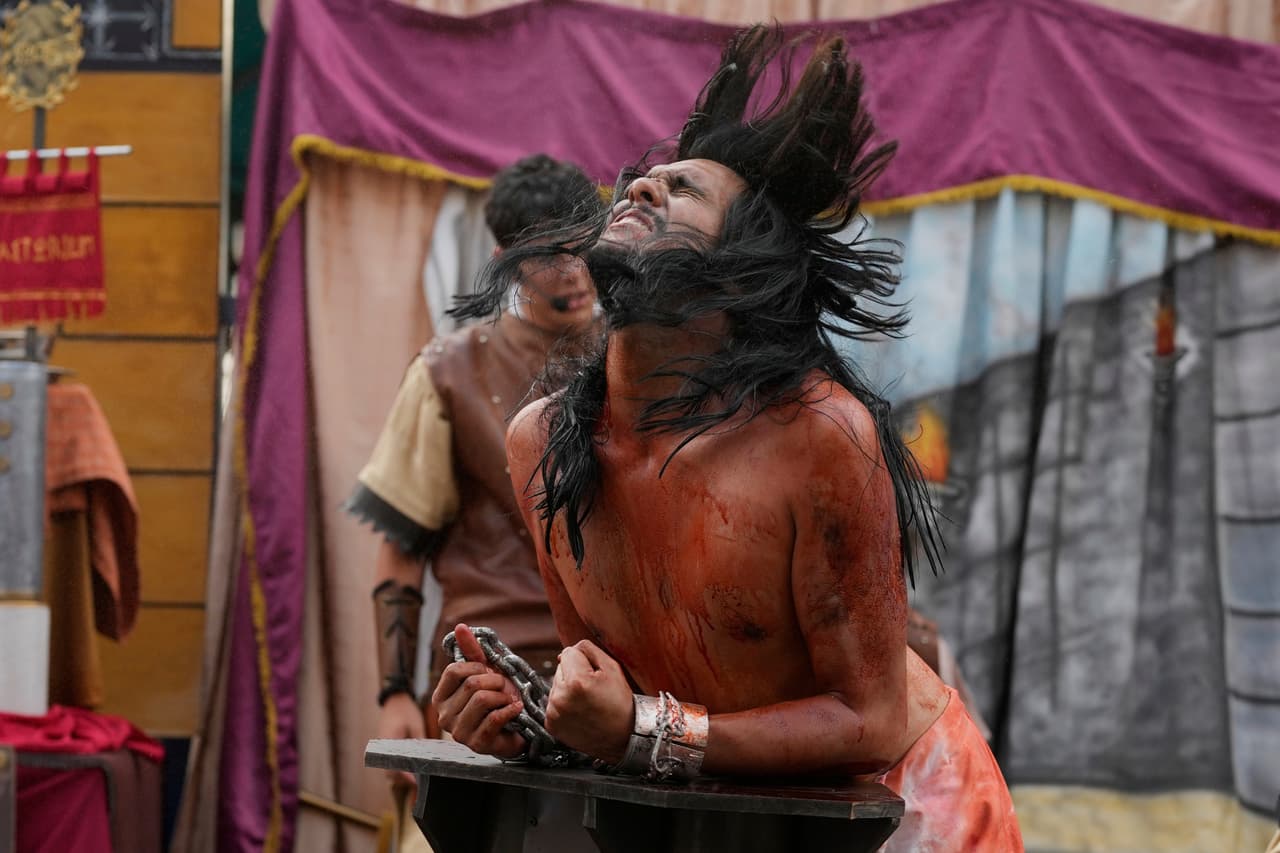 Un penitente que representa a Jesucristo es azotado por un devoto que interpreta a un soldado romano, durante una representación del Vía Crucis como parte de las celebraciones de Semana Santa en el barrio Petare de Caracas, Venezuela, el Viernes Santo, 18 de abril de 2025.