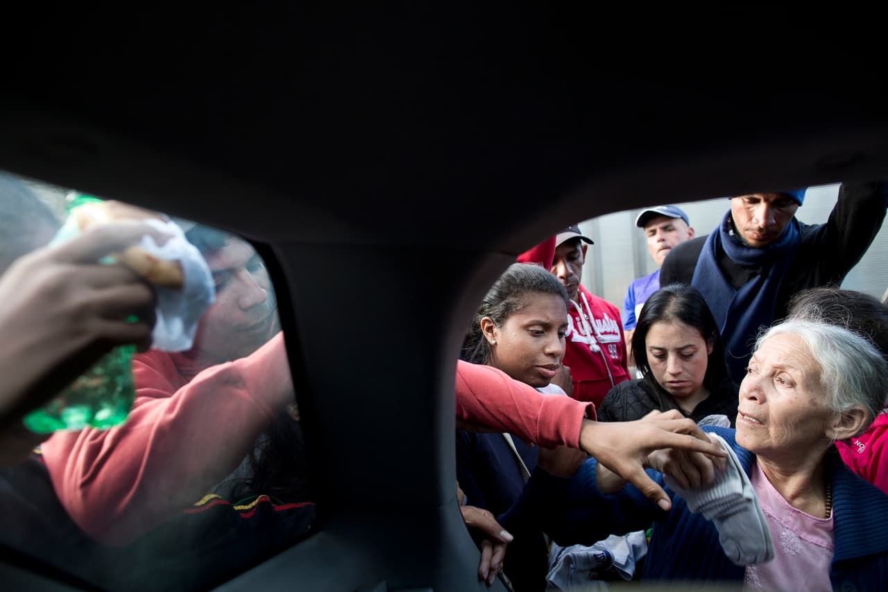Familias ecuatorianas voluntarias reparten ayuda en el terminal de buses de Cárcelen (norte de Quito), donde muchos de los migrantes venezolanos duermen esperando conseguir dinero para seguir su camino hacia Perú.