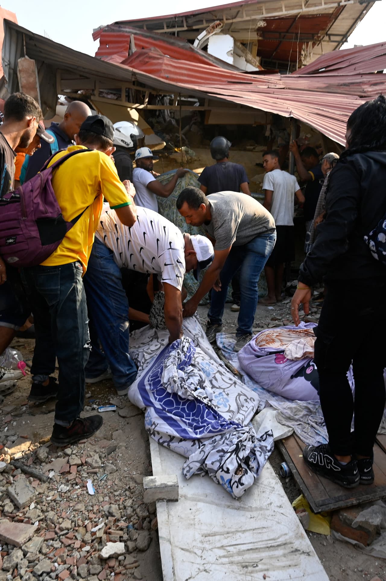 Varias personas cubren el cuerpo de una víctima entre los escombros de los edificios dañados tras los terremotos en La Guaira, Venezuela, el 25 de junio de 2026.