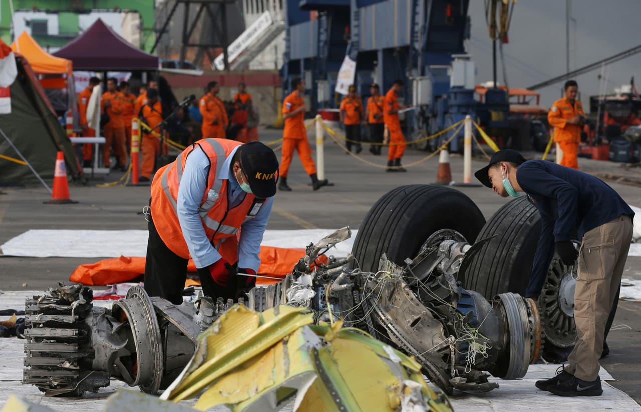 Ingenieros inspeccionan las partes del avión que han sido recuperadas.