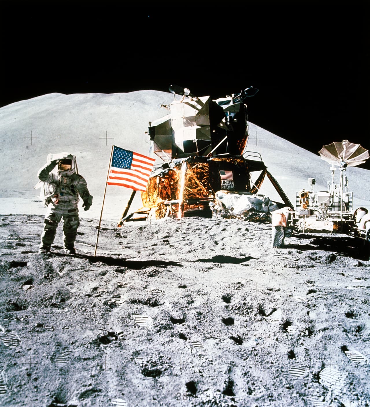 El astronauta James Irwin, con el buggy lunar y el módulo lunar saluda a la bandera estadounidense plantada en la superficie de la luna. El monte Hadley sirve de fondo a la imagen.