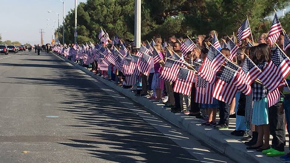 Numerosos niños ondearon banderas al paso de la carroza fúnebre.