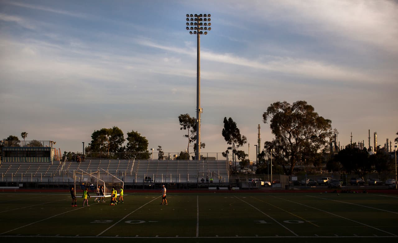 Resulta muy chocante ver correr a hispanos tras un balón de fútbol o hacer ejercicio intenso a niños delante de un bosque de chimeneas o justo al lado de un río de camiones que entran y salen del puerto.