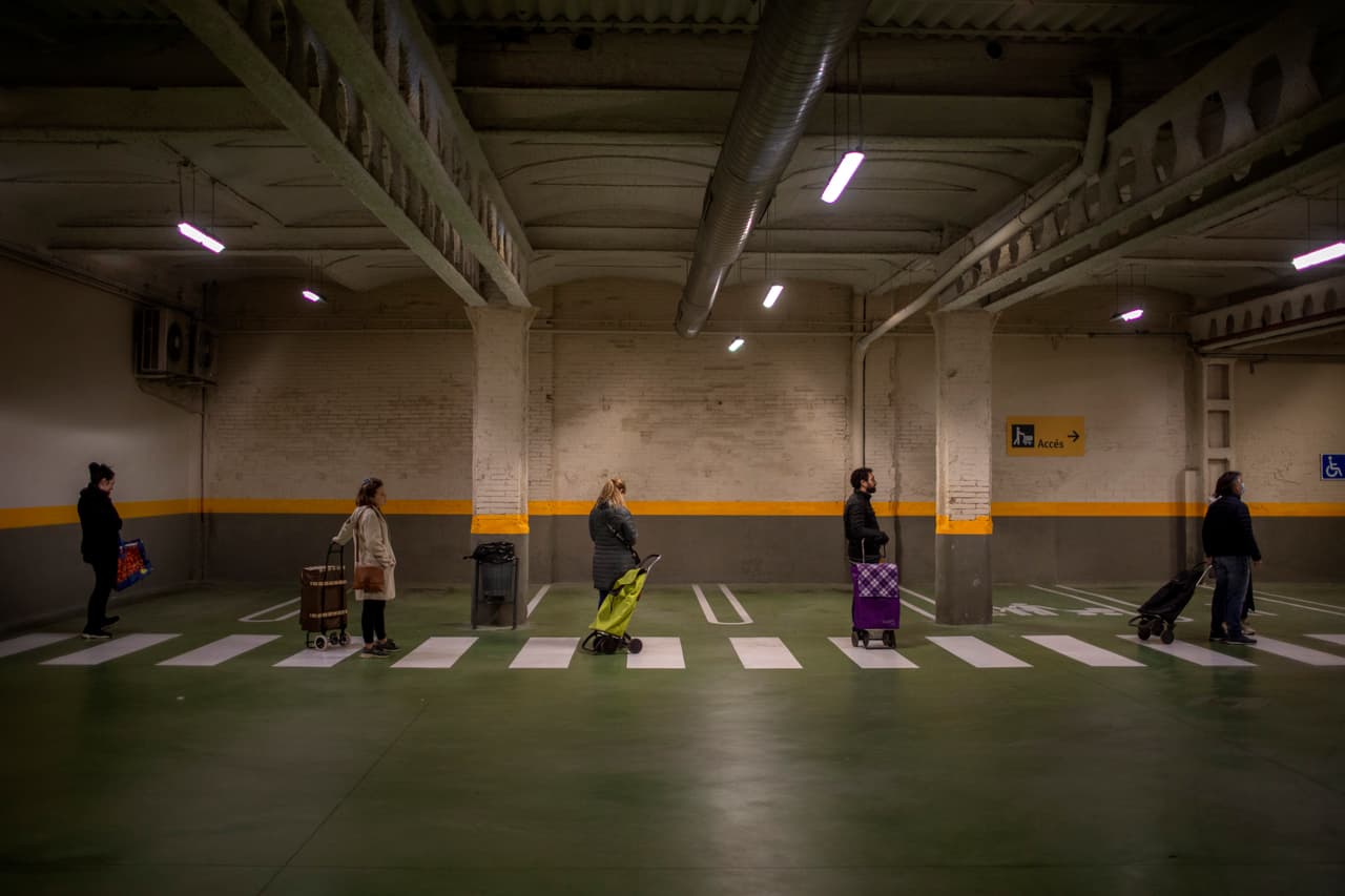 Un grupo de personas forman una línea a la puerta de un supermercado en Barcelona.