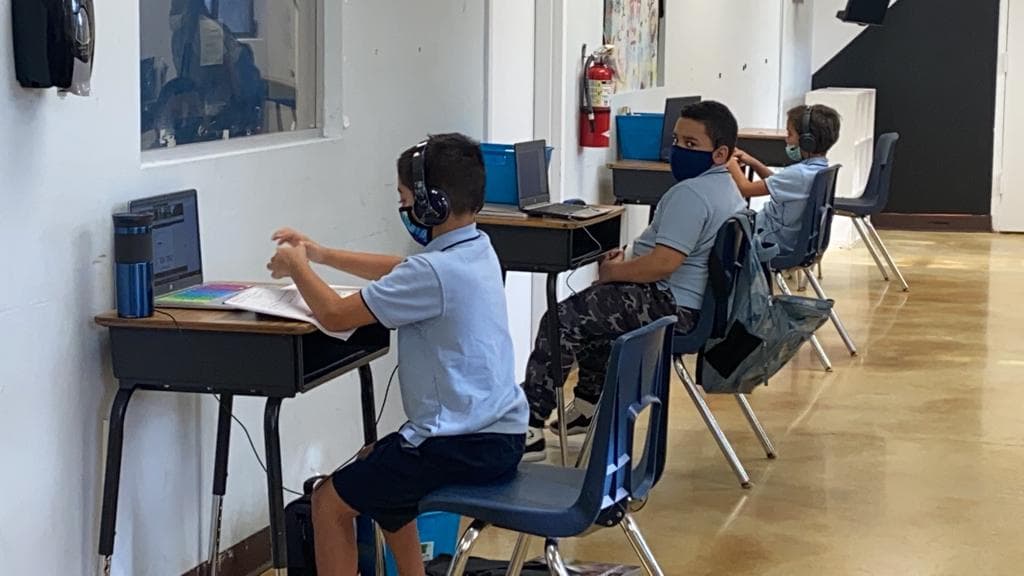 Los niños tienen que ir con su computadora, máscara facial y audífonos para escuchar su clase a través de internet.