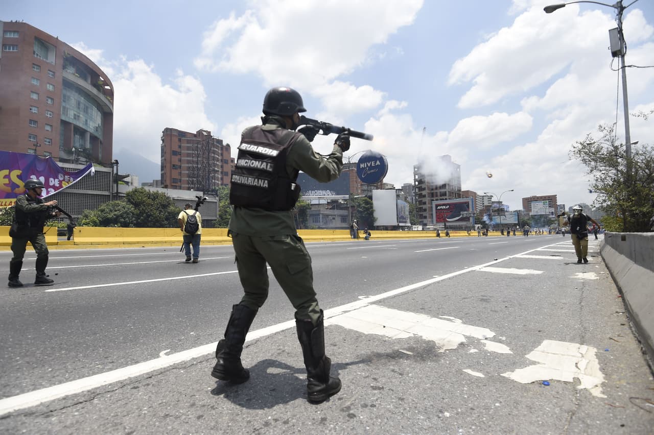 Un soldado de la Guardia Nacional apunta a un periodista con una escopeta de perdigones durante una protesta en la autopista Francisco Fajardo de Caracas.