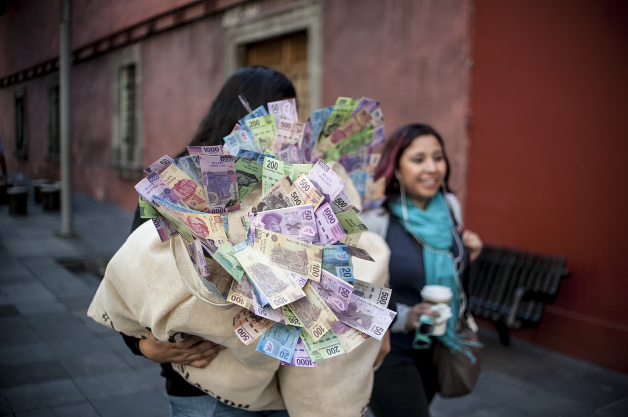 Una mujer carga un costal lleno de dinero durante una protesta en la Ciudad de México.
