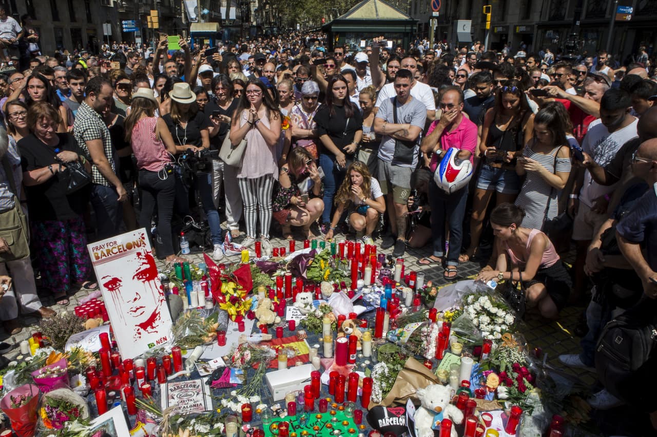 Cientos de ciudadanos se han acercado el viernes en la mañana a La Rambla para dejar flores y velas encendidas, frente a la casa de la ópera de la ciudad, sobre un cartel con el lema "Catalunya, lloc de pau" (Cataluña, lugar de paz).