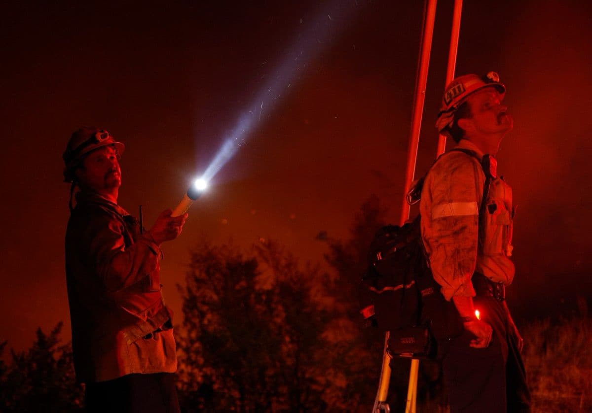 Otro ángulo de los bomberos observando el desastre causado por el fuego, la temperatura y los vientos.