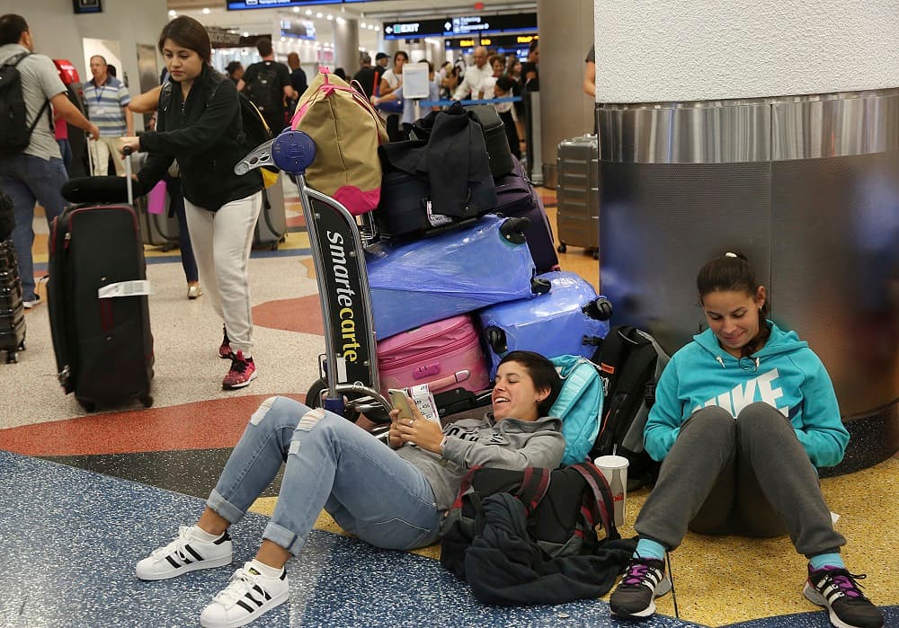 Yanina Fernandez, left, and her sister Liz, wait for an available flight to Argentina after their flight was cancelled at Miami International Airport, Thursday, Sept. 7, 2017, in Miami. South Florida officials are expanding evacuation orders as Hurricane Irma approaches, telling more than a half-million people to seek safety inland. (AP Photo/Marta Lavandier)