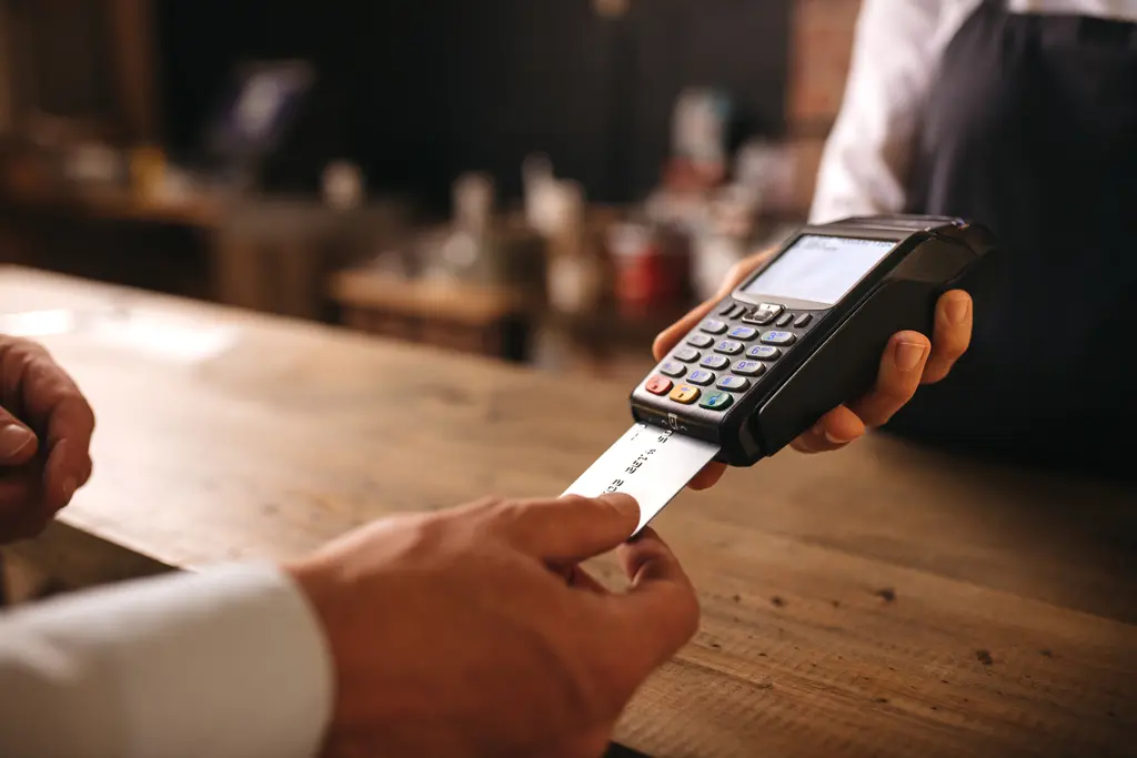 Customer inserting his credit card in the machine to payment at cafe. Customer paying for their order with a credit card in a cafe, with bartender holding a credit card reader machine.