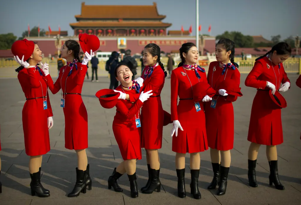 Hospitality staff members laugh as they stand on Tiananmen Square before the closing ceremony of China's 19th Party Congress at the Great Hall of the People in Beijing, Tuesday, Oct. 24, 2017. The ruling Communist Party on Tuesday formally lifted Xi Jinping's status to China's most powerful ruler in decades, setting the stage for the authoritarian leader to tighten his grip over the country while pursuing an increasingly muscular foreign policy and military expansion. (AP Photo/Mark Schiefelbein)